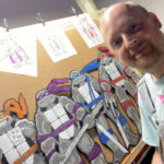 Artist Garald (Gary) Barton IV in his studio, next to his easel, with the 4 Teenage Mutant Ninja Turtle paintings.
